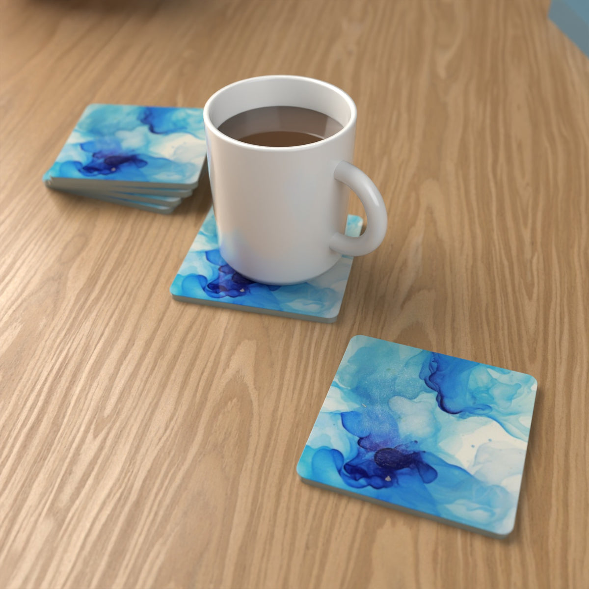 Blue Swirl Marble square glass coasters on an oak coffee table with a mug – lifestyle mockup 1
