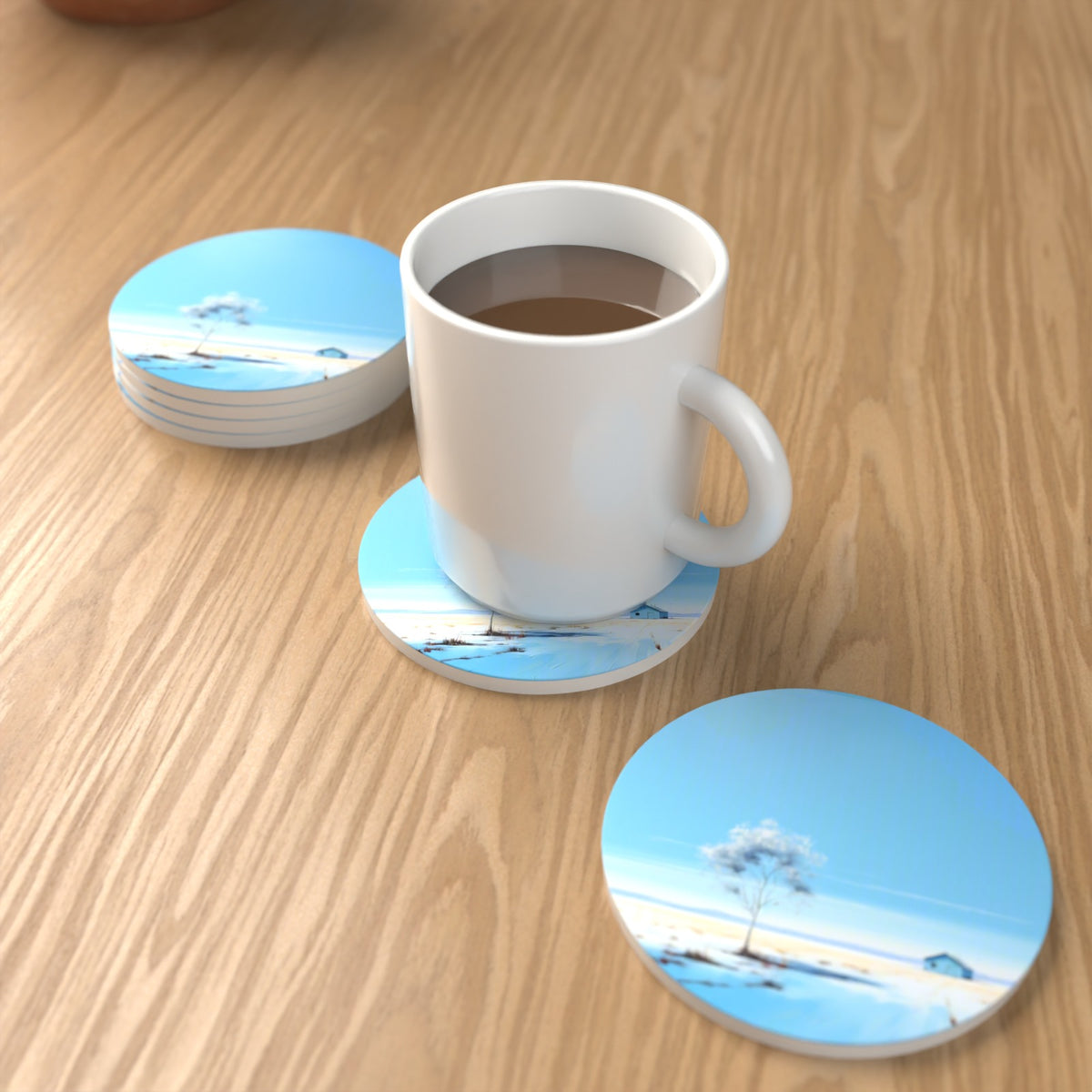 Lone Tree in a Snowy Field Round Ceramic Coasters – Set of 6 – lifestyle mockup with a mug of coffee