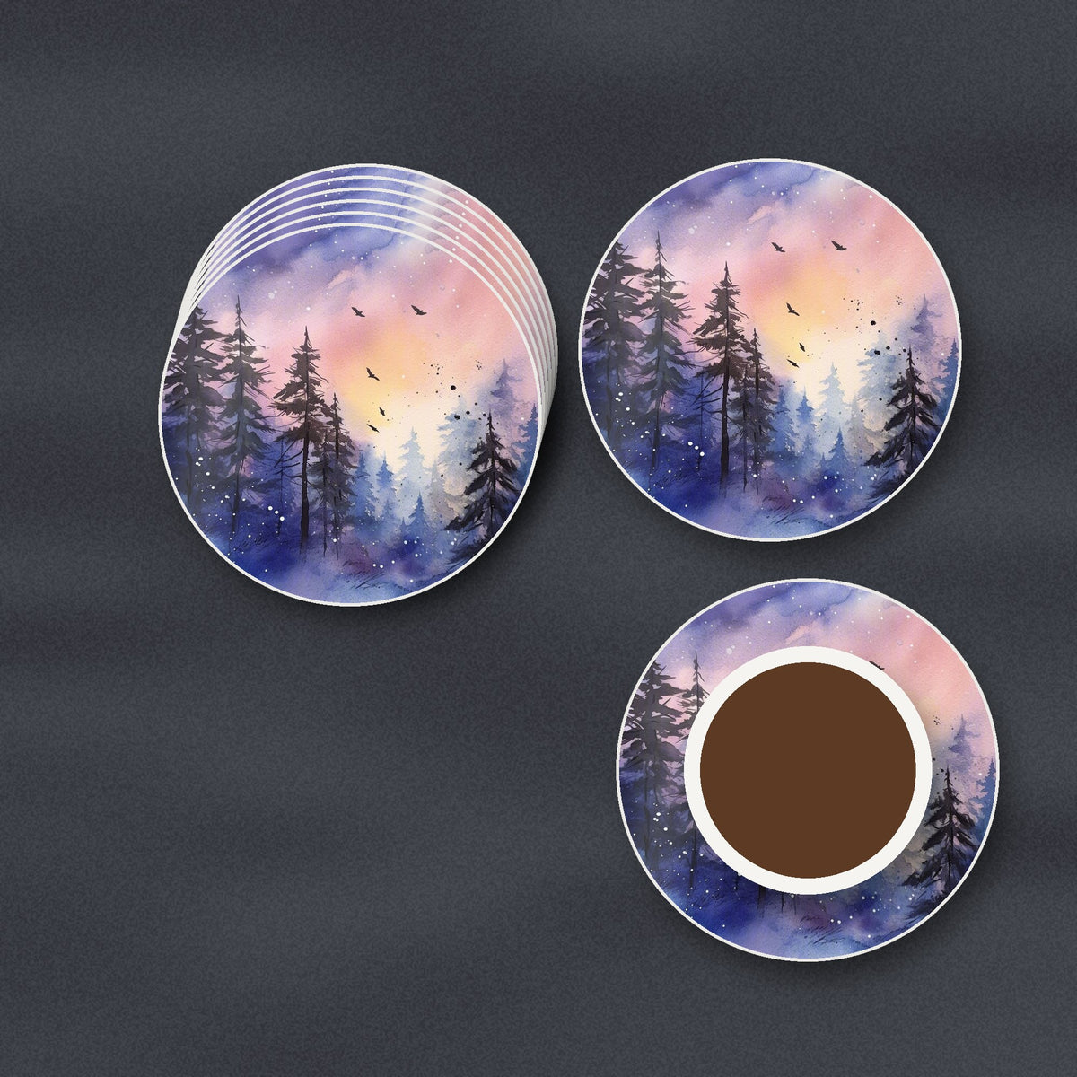 Watercolour Winter Pine Forest round ceramic coasters stacked on a slate kitchen worktop