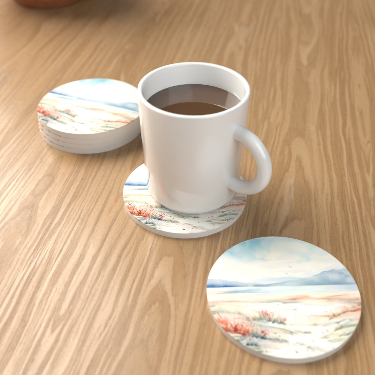 Watercolour Winter Shore Round Ceramic Coasters – Set of 6 – lifestyle mockup with a mug of coffee