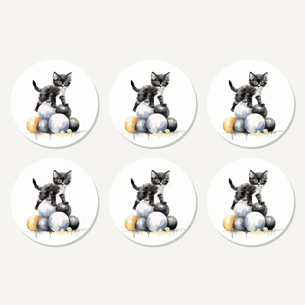 Flat lay of the black kitten on a pile of balls artwork on six round coasters