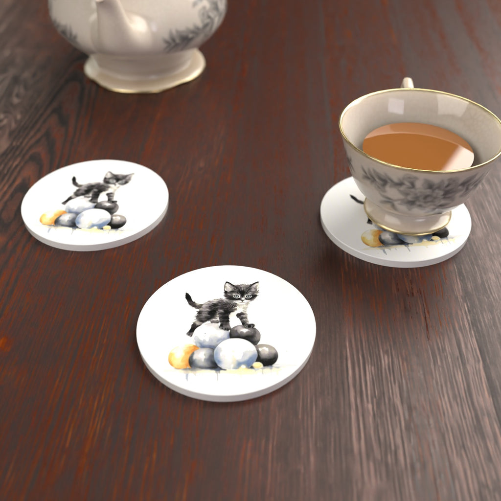 Black Kitten on a Pile of Balls Round Ceramic Coasters – Set of 6 – lifestyle mockup with a teacup