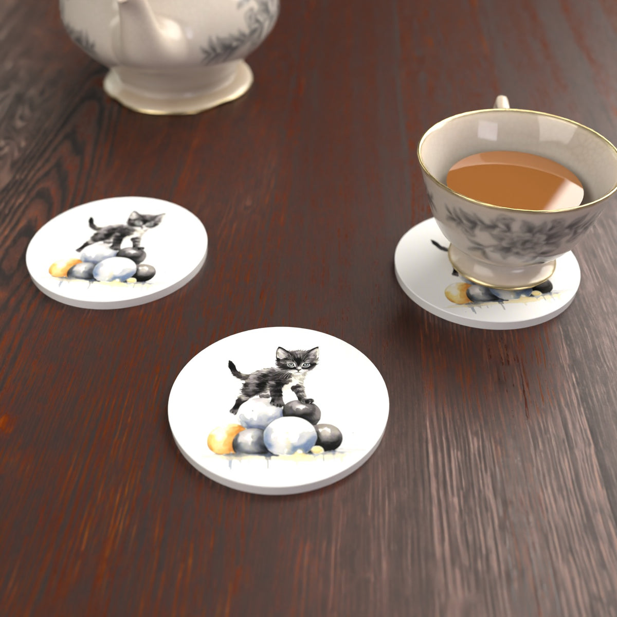 Black Kitten on a Pile of Balls Round Ceramic Coasters – Set of 6 – lifestyle mockup with a teacup