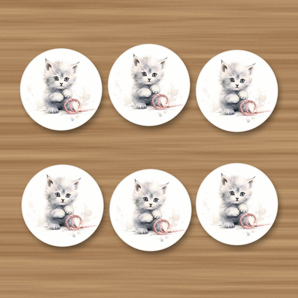 White Kitten with Yarn round ceramic coasters, set of 6, on an oak coffee table