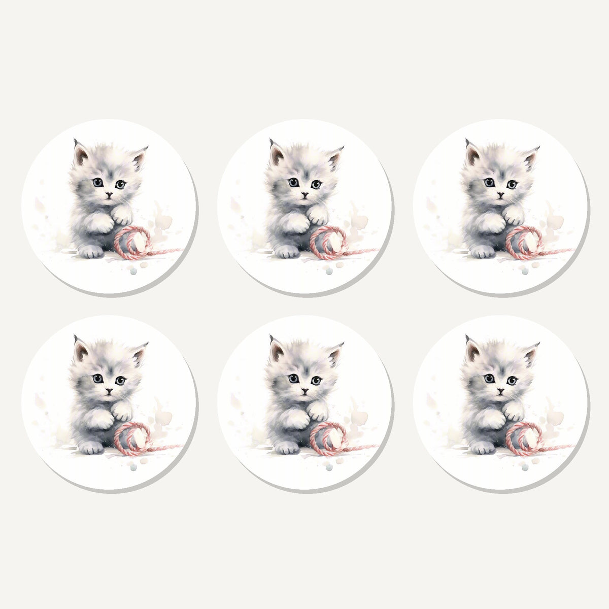 Flat lay of the white kitten with yarn artwork on six round coasters