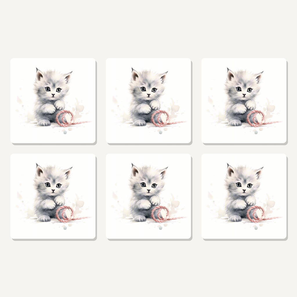 Flat lay of the white kitten with yarn artwork on six square coasters