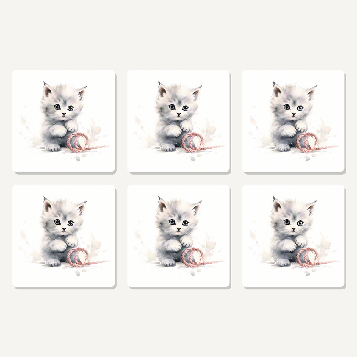 Flat lay of the white kitten with yarn artwork on six square coasters