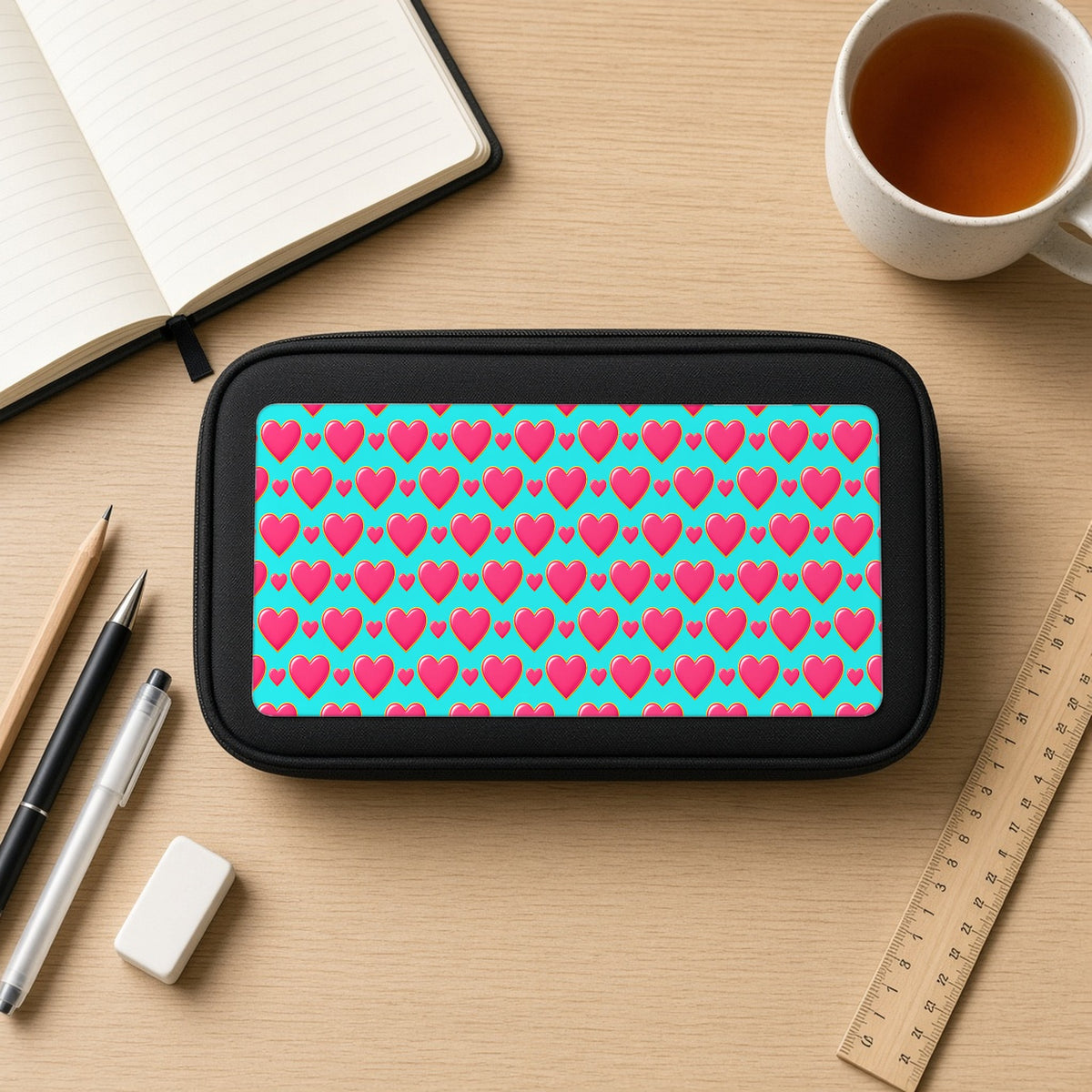 Heart Bubble Grid pencil case on a wooden desk with notebook, pens and a cup of tea