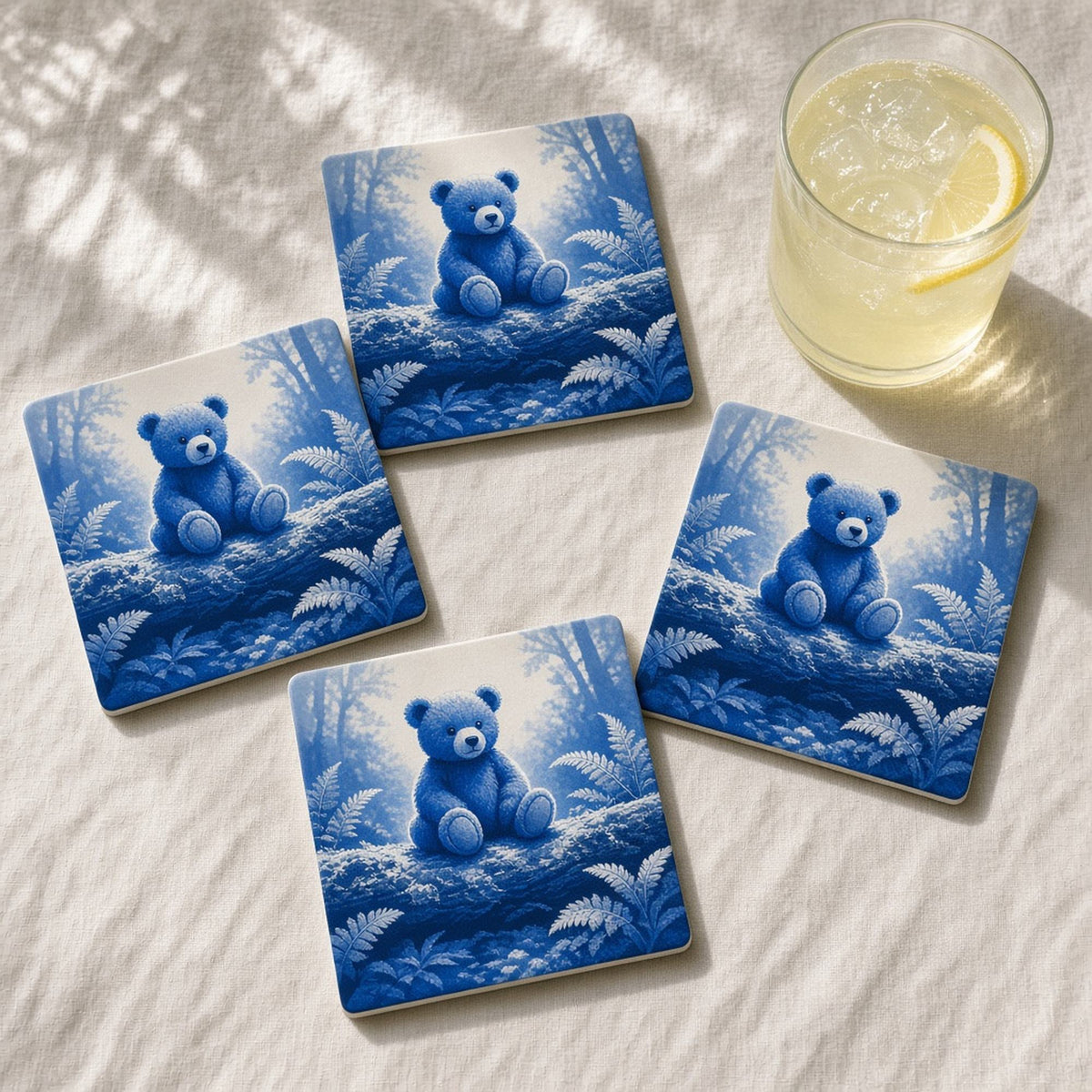 Monochrome cobalt-blue lost teddy bear sitting on a mossy log in a sunlit fern clearing printed flat on a set of 4 coasters, made with prompt #227