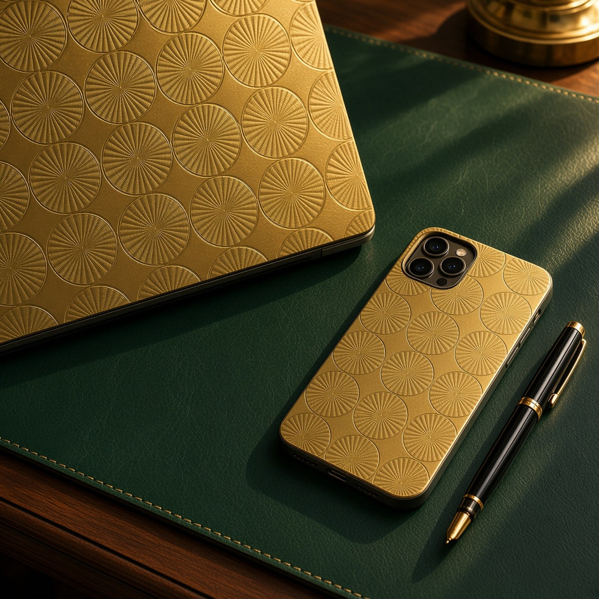 Laptop skin and phone case in brass engine-turned metal circles on a green leather desk, made with prompt #121
