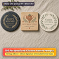 Three personalised kitchen coasters on linen: a slate coaster with a gold laurel ring, an oak coaster with a terracotta folk teapot and a ceramic coaster with a herb garland, reading NAME'S KITCHEN, DD.MM.YYYY, YOUR MESSAGE, KITCHEN TITLE and FAMILY NAMES as placeholder text, made with prompt #1 + #63 + #17