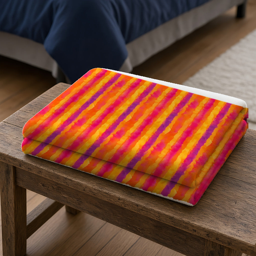 Bleed Stripe Ombre Sherpa Fleece Blanket folded on a wooden bench