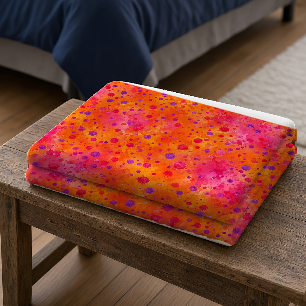 Pigment Dot Bleeds Sherpa Fleece Blanket folded on a wooden bench