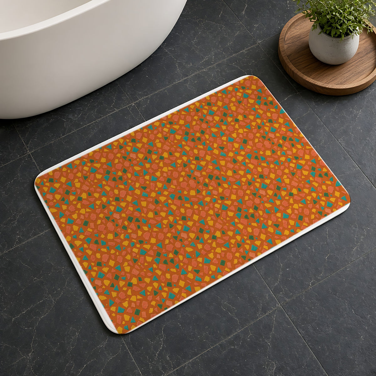 Angular Shard Scatter Bath Mat on a dark slate floor beside a bath