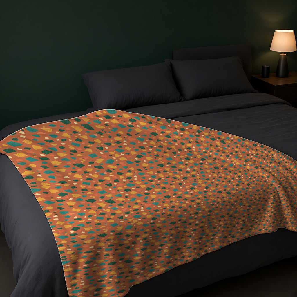 Jewel Chip Terrazzo Sherpa Fleece Blanket across the foot of a dark bed