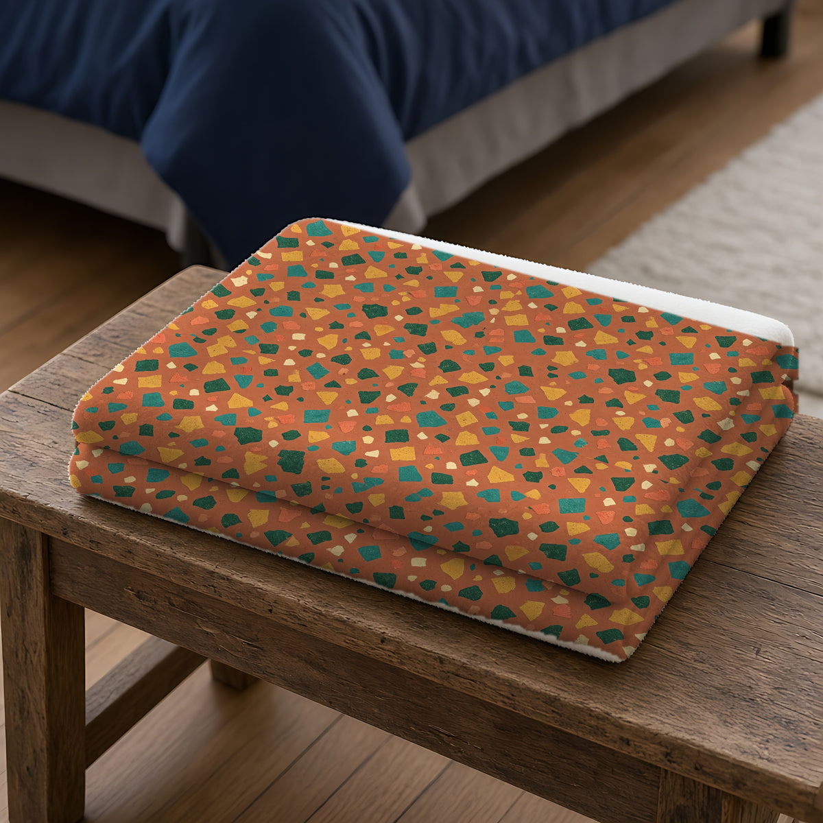 Jewel Chip Terrazzo Sherpa Fleece Blanket folded on a wooden bench