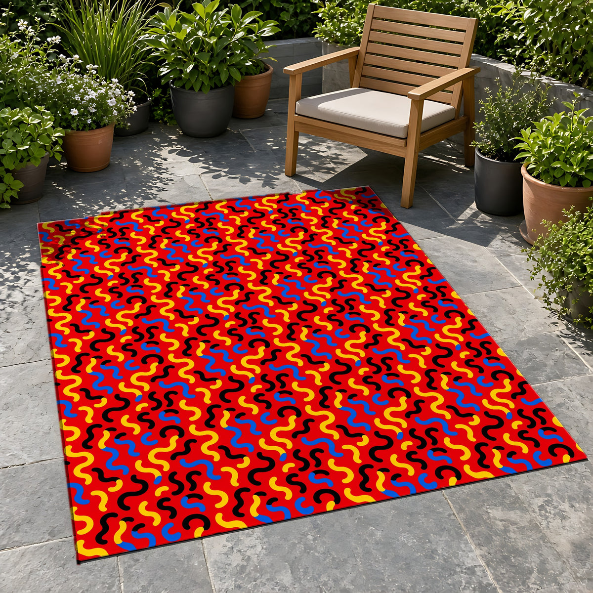 Squiggle Red Outdoor Rug on a stone patio with potted plants