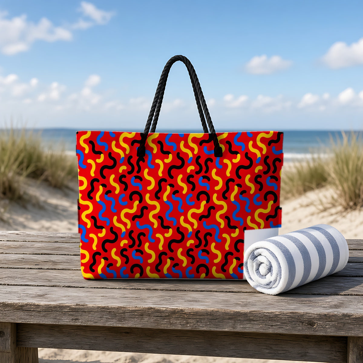 Squiggle Red Weekender Tote Bag on a rustic table by the beach