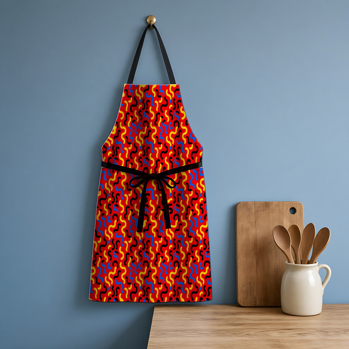 Squiggle Red Apron hanging in a blue kitchen