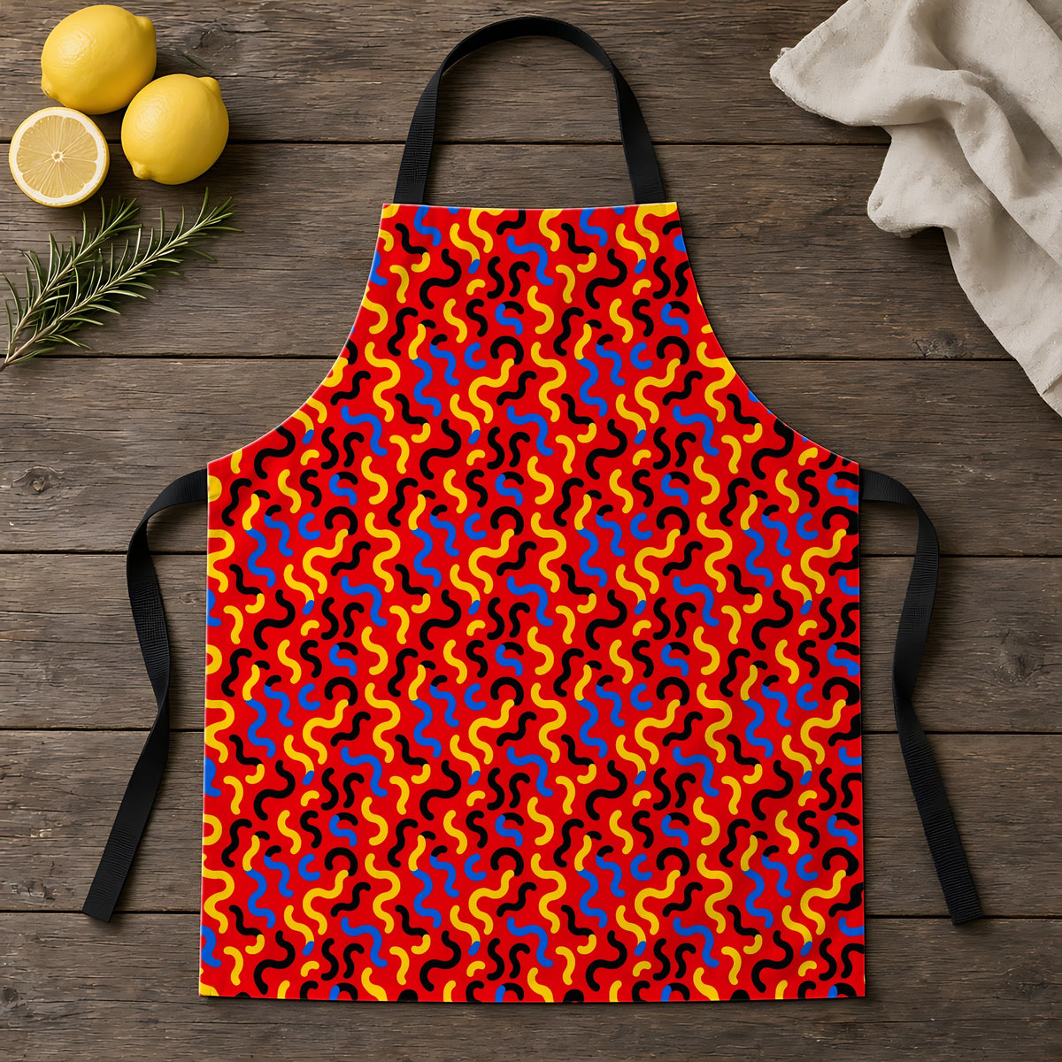 Squiggle Red Apron laid flat on a rustic wooden table