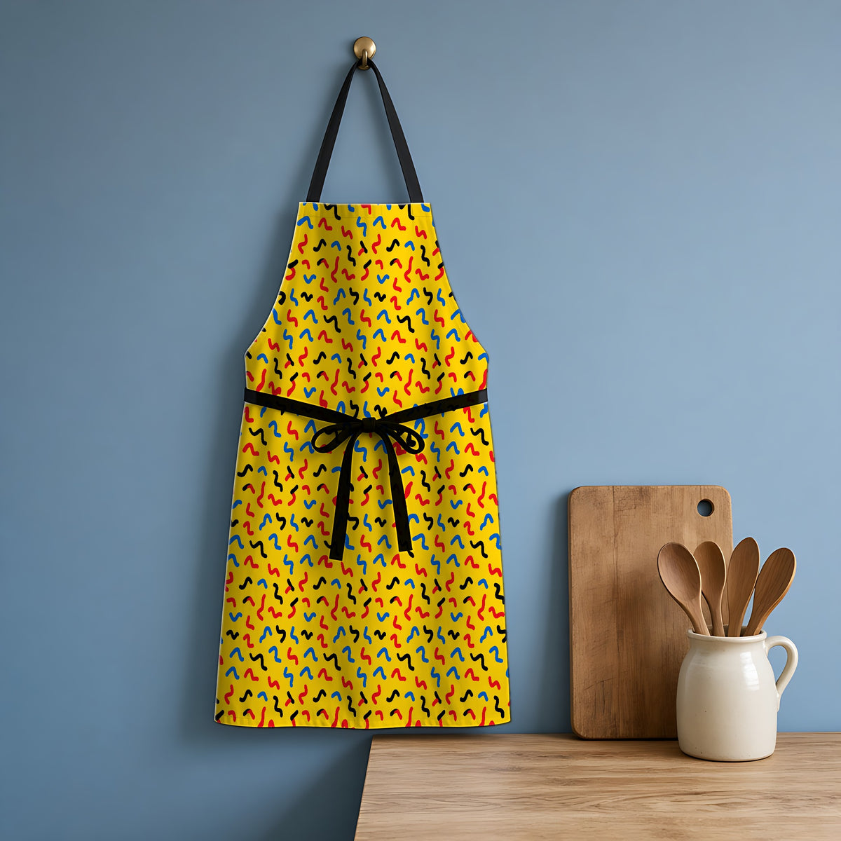 Squiggle Strokes Yellow Apron hanging in a blue kitchen