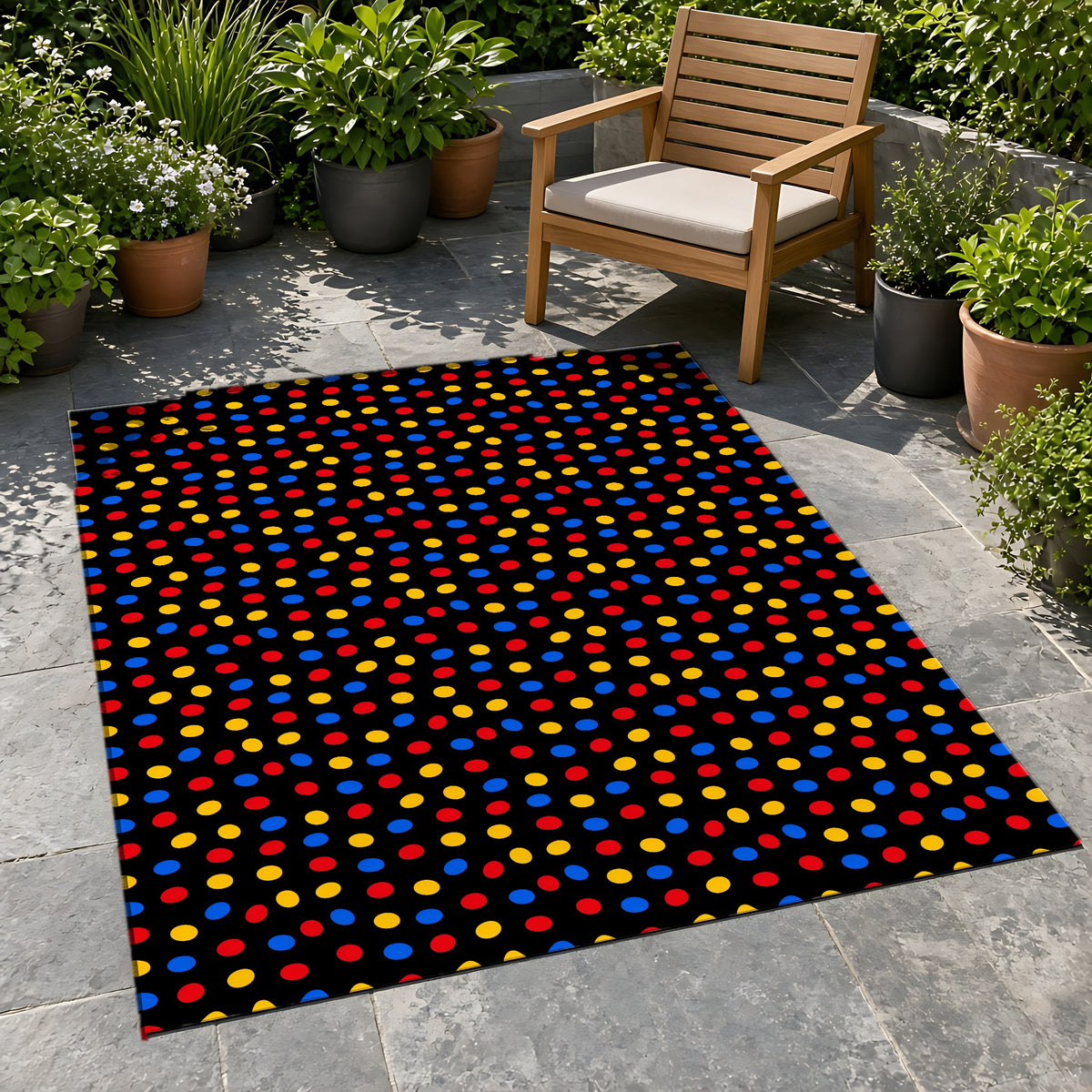 Pebble Scatter Black Outdoor Rug on a stone patio with potted plants