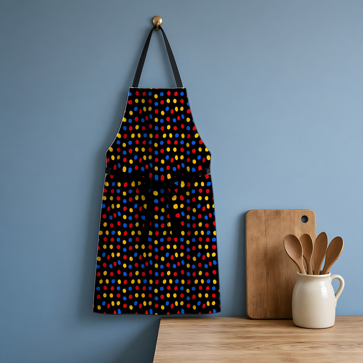 Pebble Scatter Black Apron hanging in a blue kitchen