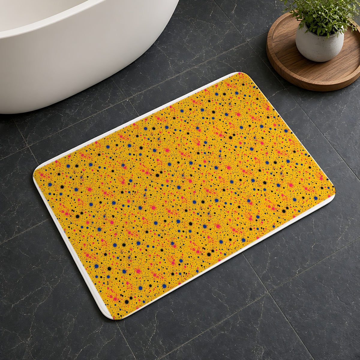 Pink Spray Field Bath Mat on a dark slate floor beside a bath