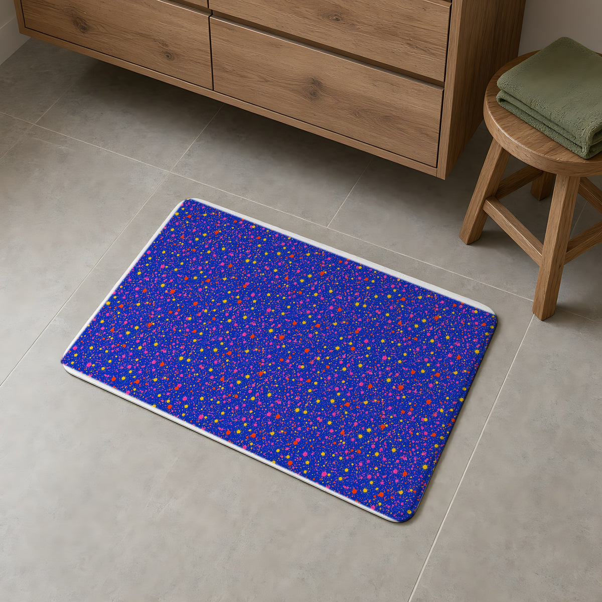 Ultramarine Spatter Bath Mat on a grey tiled bathroom floor