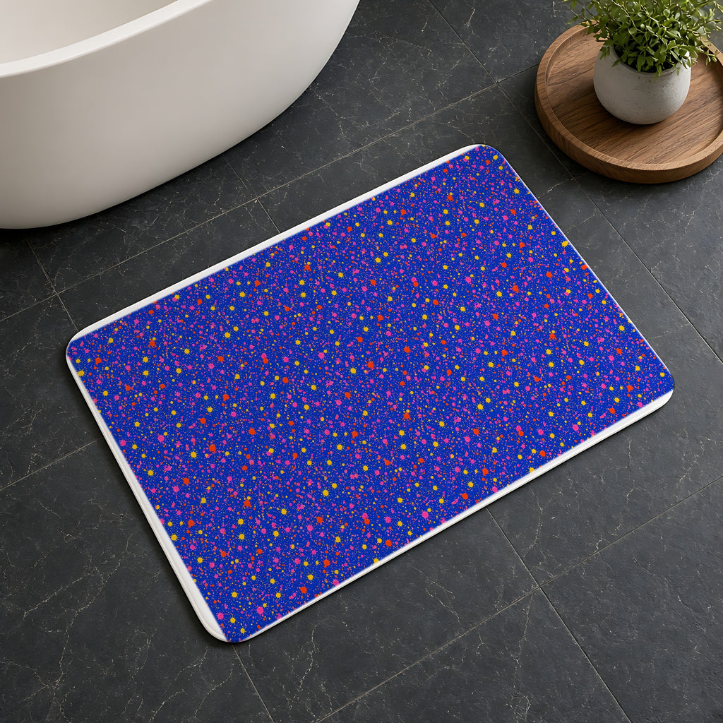 Ultramarine Spatter Bath Mat on a dark slate floor beside a bath
