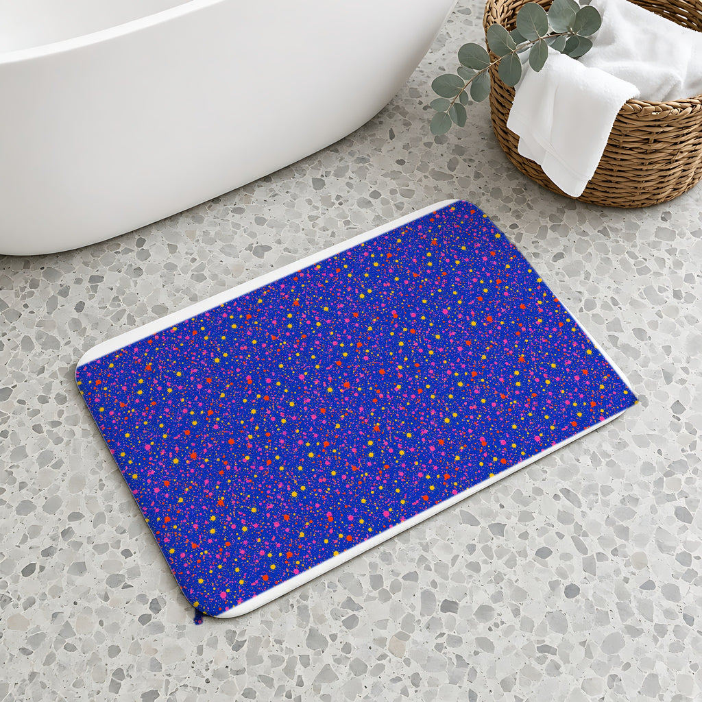 Ultramarine Spatter Bath Mat on a terrazzo floor beside a freestanding bath