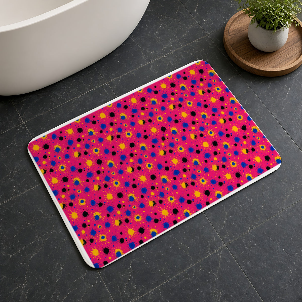 Pink Ground Splash Bath Mat on a dark slate floor beside a bath