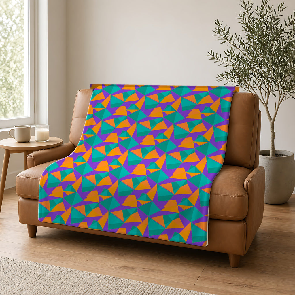 Faceted Gold Panels Sherpa Fleece Blanket draped over a caramel leather sofa