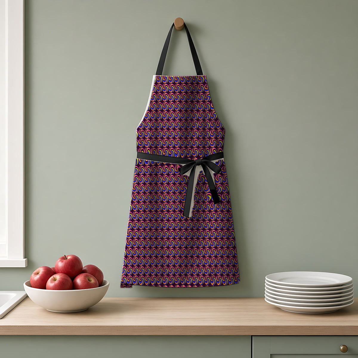 Spiral Stripe Swirls Apron hanging on a sage-green kitchen wall