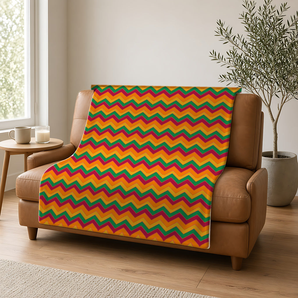 Jewel Chevron Bands Sherpa Fleece Blanket draped over a caramel leather sofa