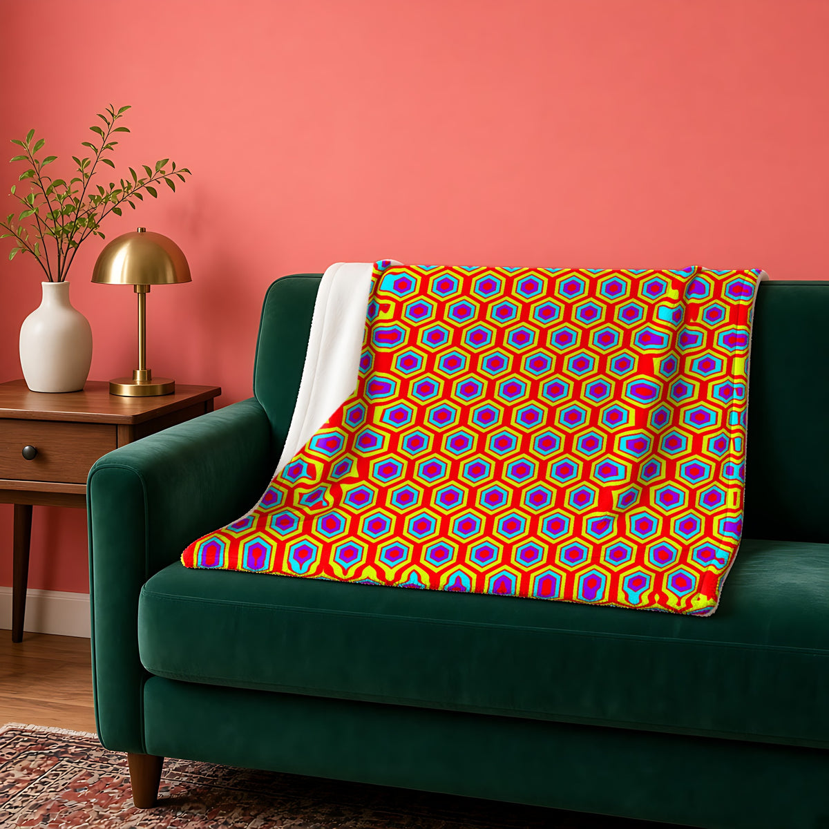 Concentric Hexagon Ripple sherpa fleece blanket in the Chromatic Ripple palette, draped over a green sofa against a coral wall