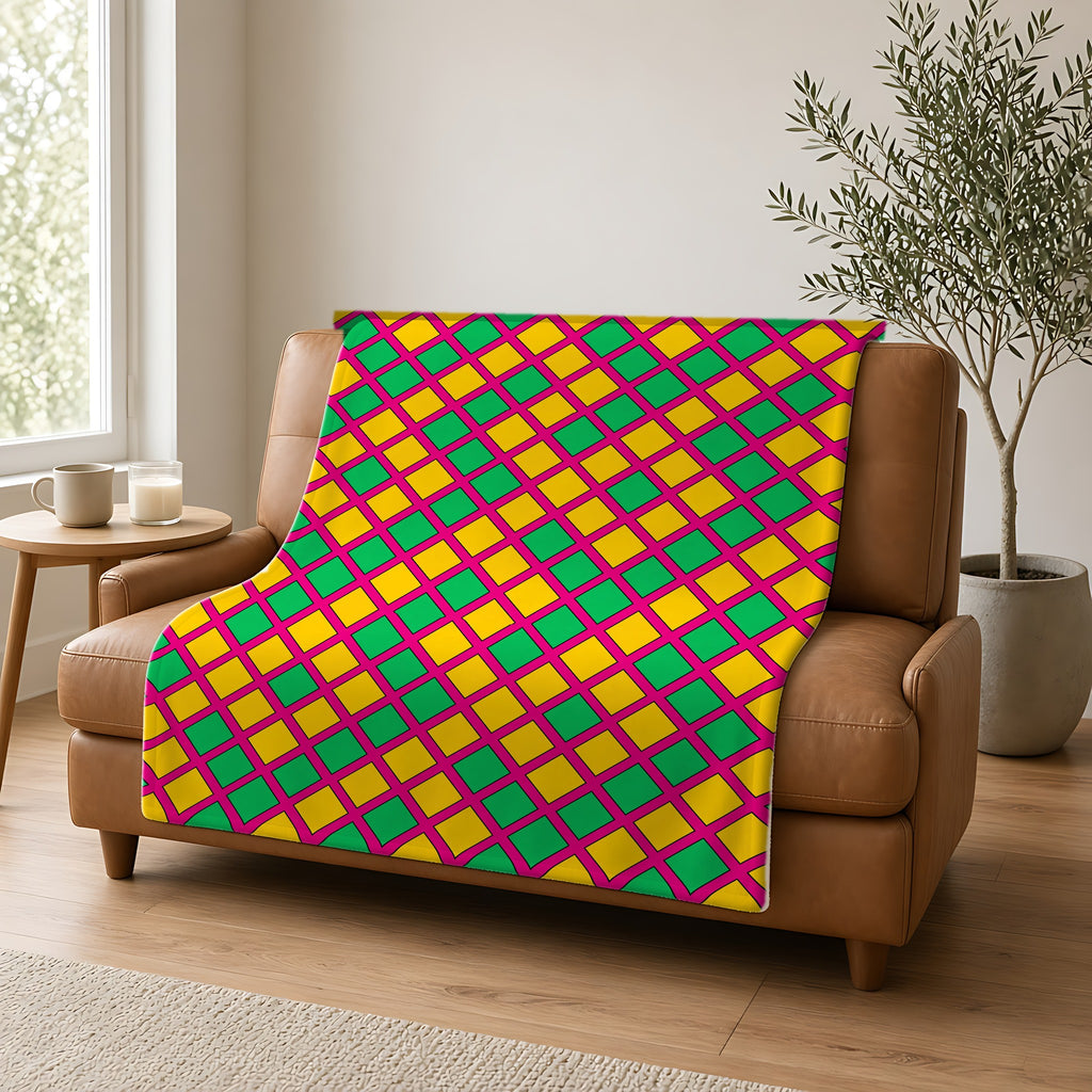 Harlequin Gold Grid Sherpa Fleece Blanket draped over a caramel leather sofa