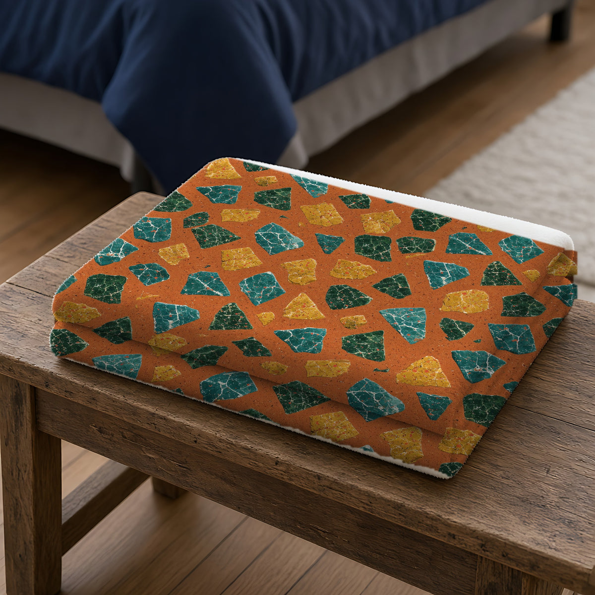 Marble Fragment Toss Sherpa Fleece Blanket folded on a wooden bench