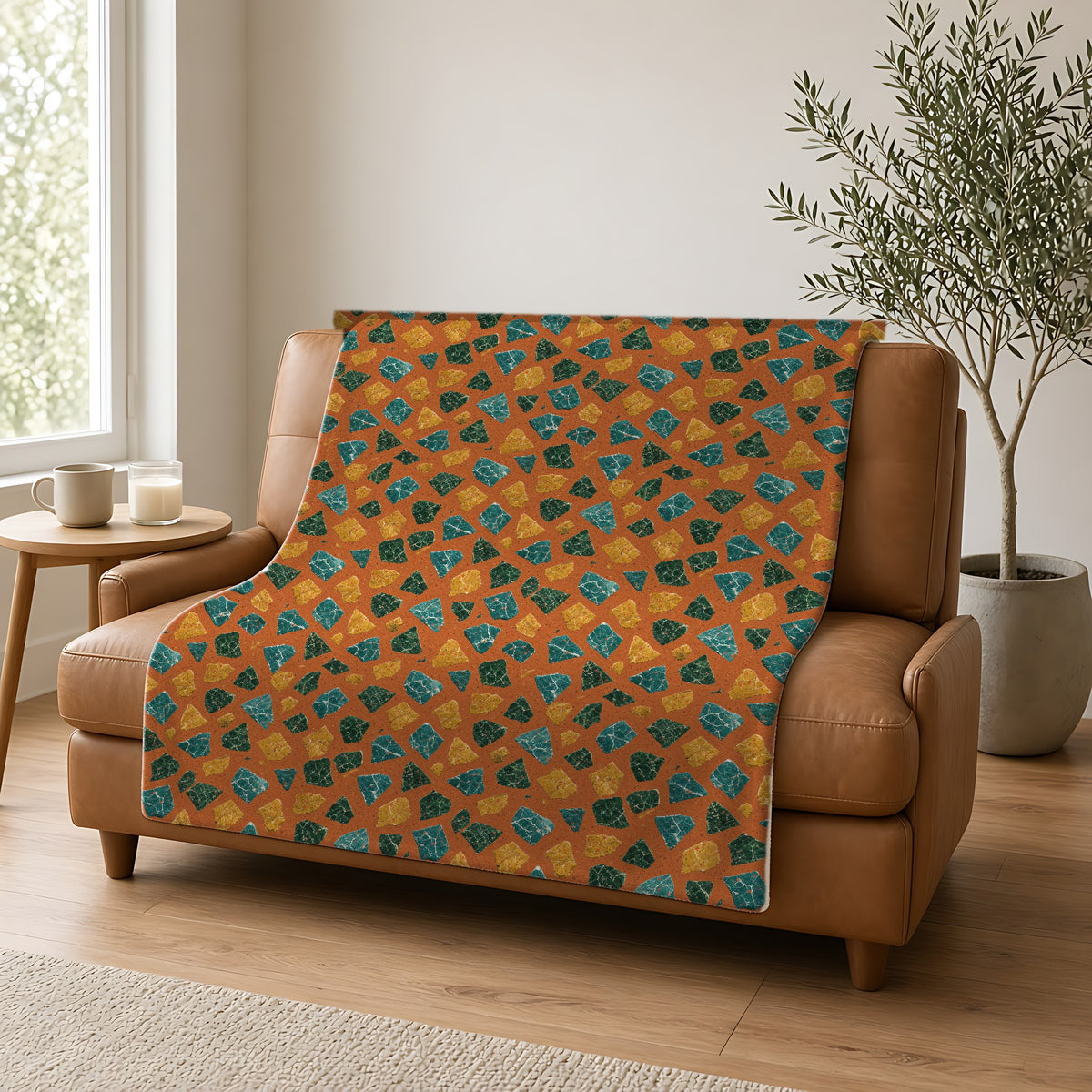 Marble Fragment Toss Sherpa Fleece Blanket draped over a caramel leather sofa