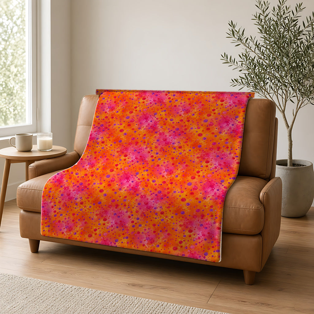 Pigment Dot Bleeds Sherpa Fleece Blanket draped over a caramel leather sofa