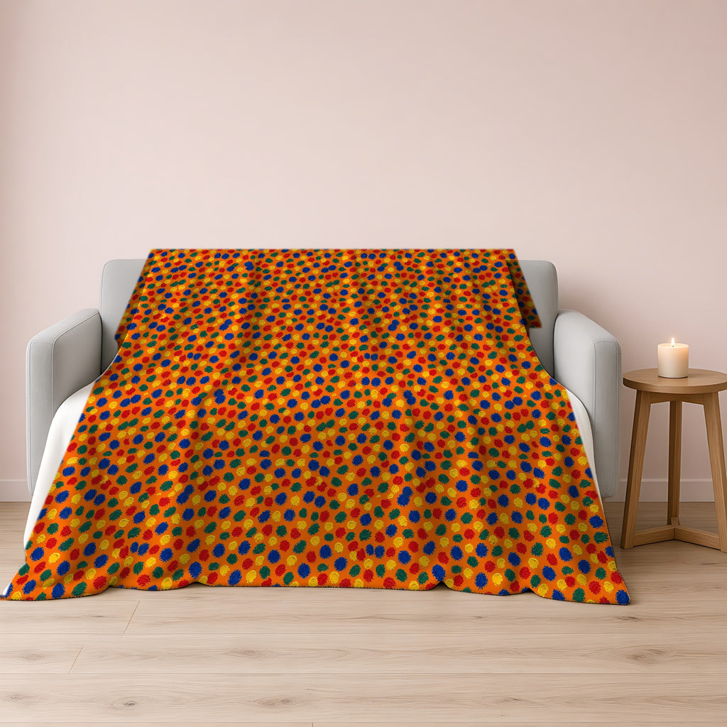 Stippled Dabs Sherpa Fleece Blanket draped over a grey sofa
