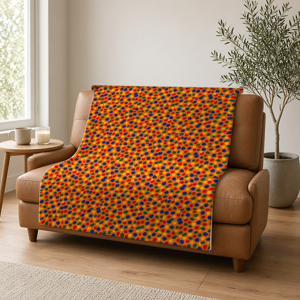Stippled Dabs Sherpa Fleece Blanket draped over a caramel leather sofa