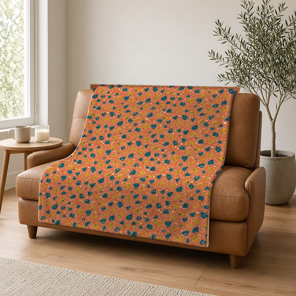 Two-Scale Chips Sherpa Fleece Blanket draped over a caramel leather sofa