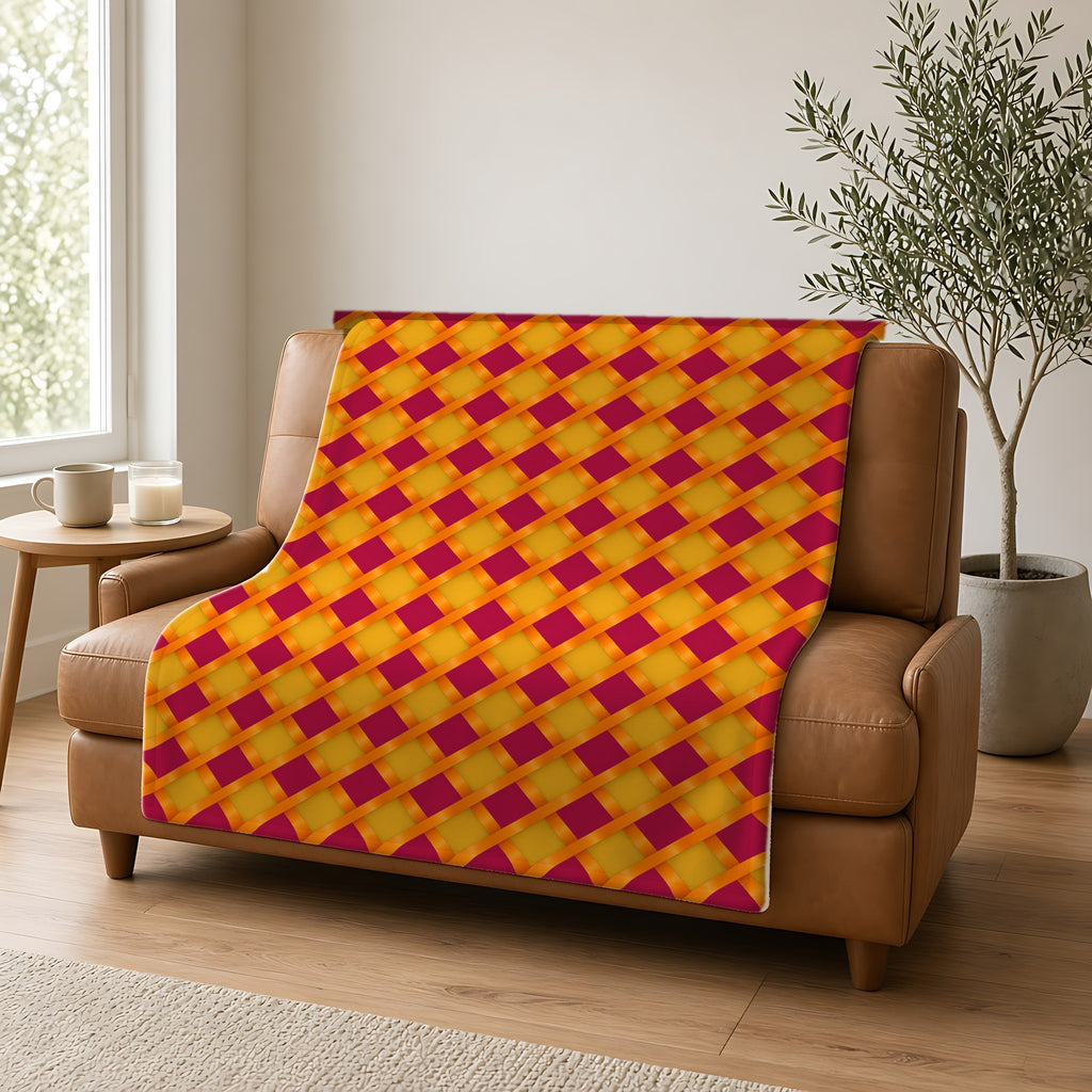 Broad Gold Diamond Trellis Sherpa Fleece Blanket draped over a caramel leather sofa