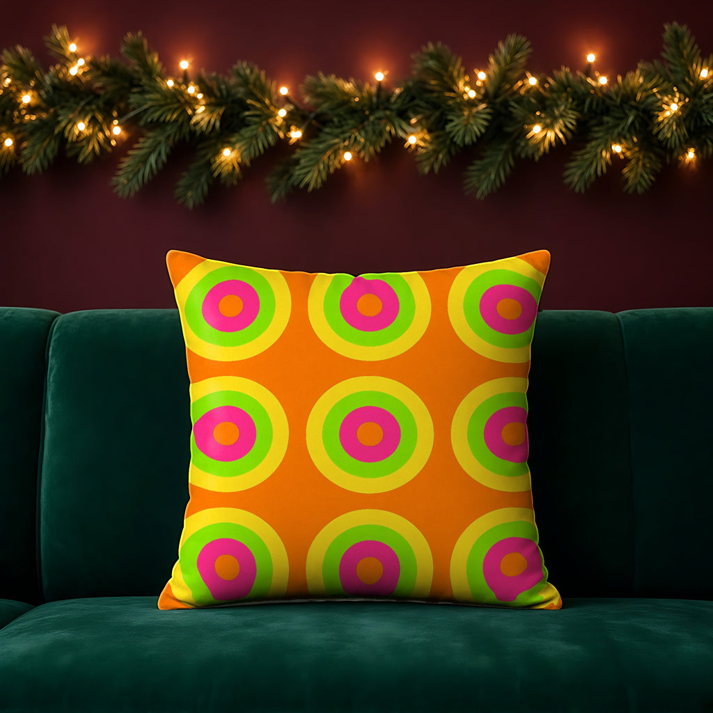 Giant Op-Art Jewel Rings Faux Suede Cushion in the Hot Citrus Festive palette, on an emerald sofa in a festive room with a garland and fairy lights
