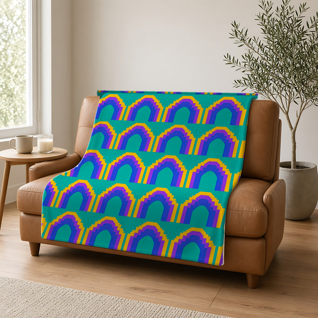 Grand Stepped Arches Sherpa Fleece Blanket draped over a caramel leather sofa