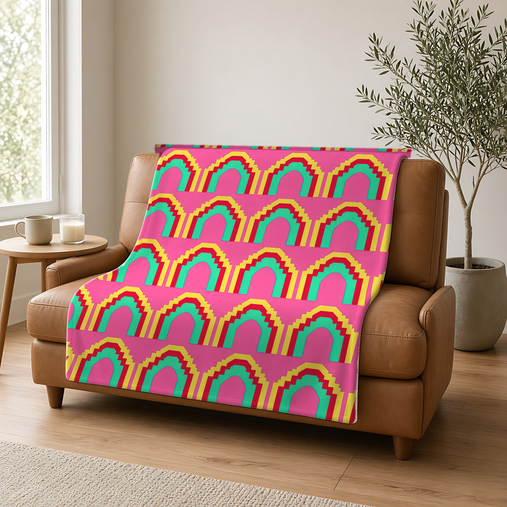 Grand Stepped Arches Sherpa Fleece Blanket draped over a caramel leather sofa