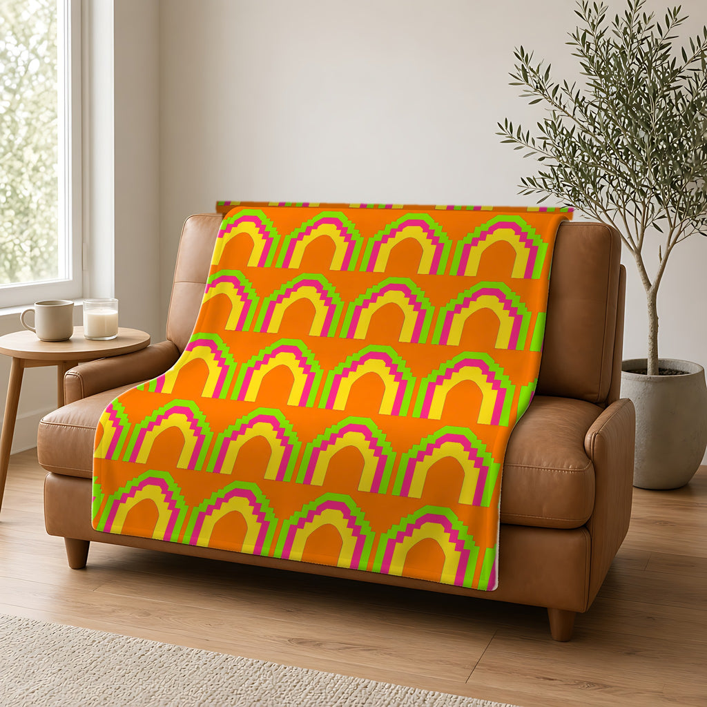 Grand Stepped Arches Sherpa Fleece Blanket draped over a caramel leather sofa