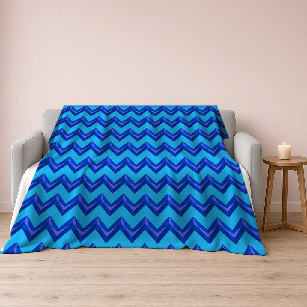 Broad Cut-Gem Chevrons Sherpa Fleece Blanket draped over a grey sofa