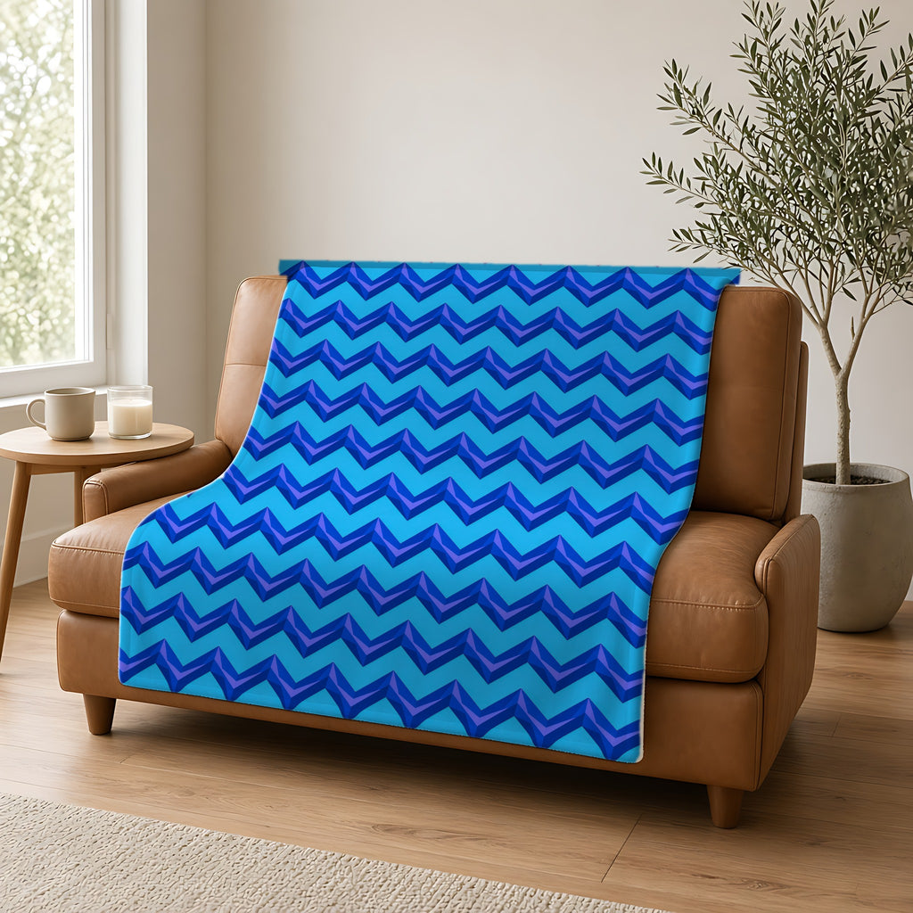Broad Cut-Gem Chevrons Sherpa Fleece Blanket draped over a caramel leather sofa